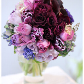 ワイン色のバラやカラーに青紫、赤紫等様々なパープルを重ねたブーケ。ゴールドの蝶を加えてロマンチックな雰囲気に。