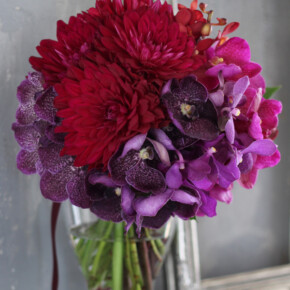 赤いダリアと紫、ワイン、ピンク系の蘭を使った大人っぽいクラッチブーケ。
花材を種類ごとにまとめて入れるグルーピングの手法でモダンでスタイリッシュに。